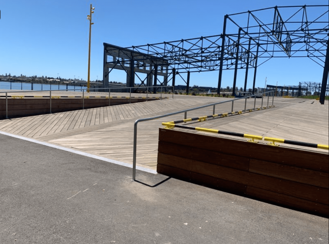 Waterfront boardwalk with metal framework overhead.